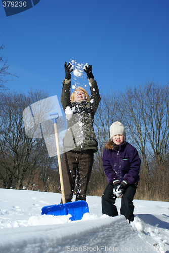 Image of mother and daughter shoveling and have fan outside