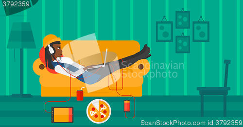 Image of Woman lying on sofa with many gadgets.