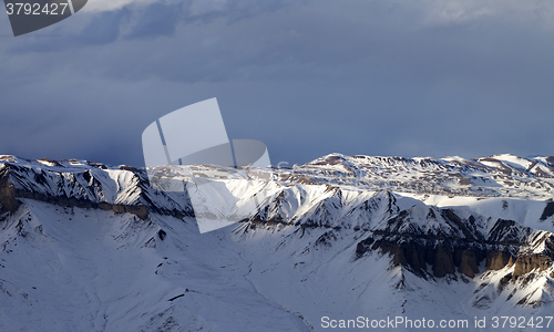 Image of Sunlight winter mountains and dark clouds at evening