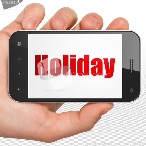 Image of Tourism concept: Hand Holding Smartphone with Holiday on display