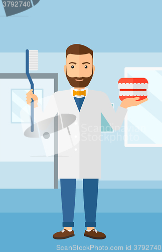 Image of Dentist with dental jaw model and toothbrush.