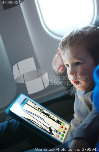 Image of Little boy drawing on a tablet in an airplane