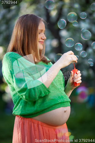 Image of Pregnant woman blowing bubbles outdoor