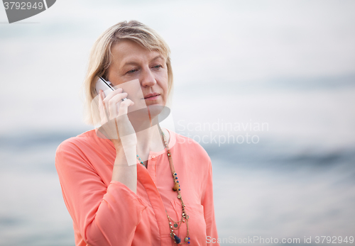 Image of Blond woman having a phone talk outdoor