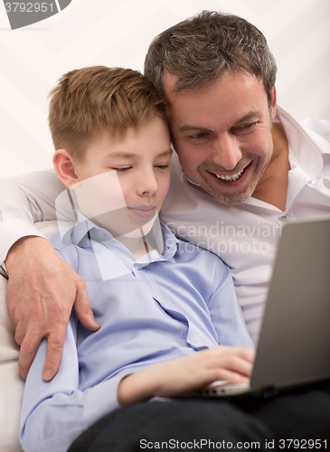 Image of Happy dad and son with laptop at home