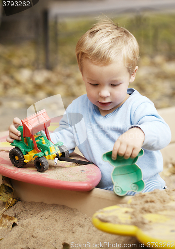 Image of Boy playing with toy outdoor.