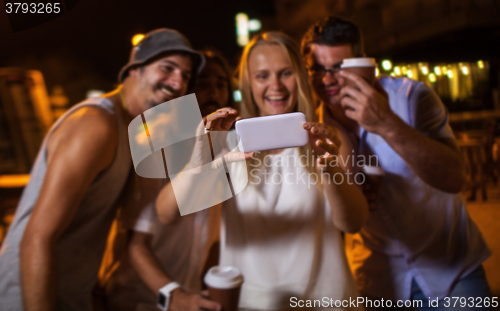 Image of Happy friends making phone selfie at night