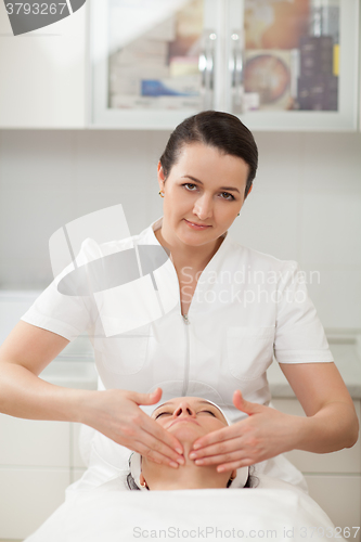 Image of Cosmetician at beauty treatment salon doing a facial massage