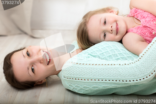 Image of Smiling mother and daughter on the floor