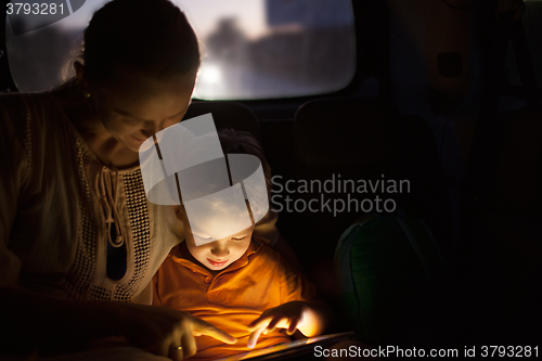 Image of Mother and son with pad during car travel at night