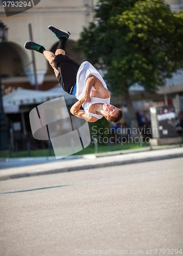 Image of Man doing acrobatic tricks in city street