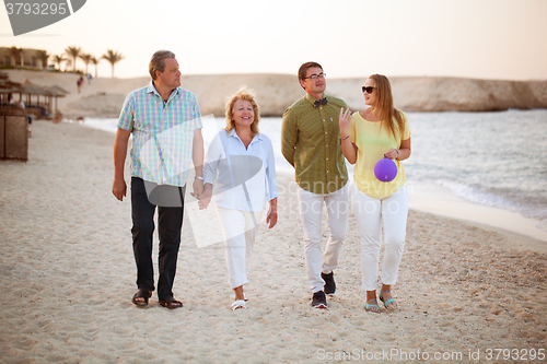 Image of Young and senior couples walking along the coast