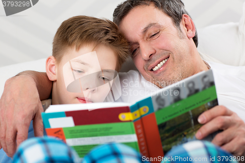 Image of Son and father reading book together