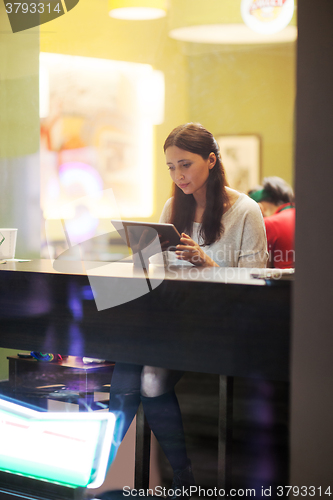 Image of Young brunette girl using tablet in the cafe