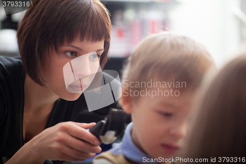 Image of Hairstylist cutting a young boys hair