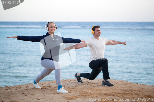 Image of Young couple working out outdoor with music