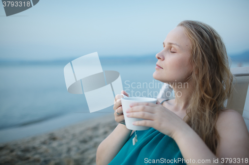 Image of Woman with closed eyes enjoying a cup of tea