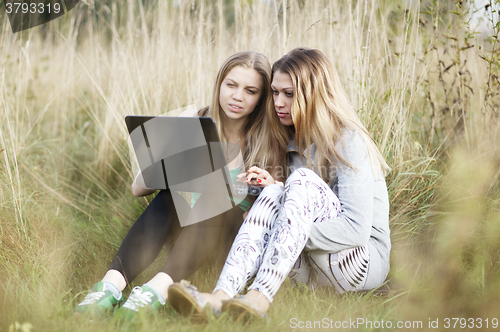 Image of Female friends with laptop outdoor