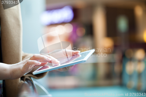 Image of Woman with tablet computer in public place