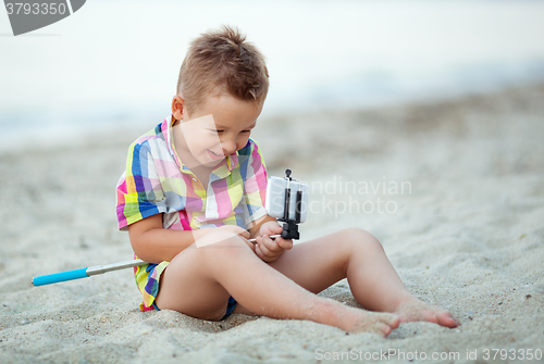 Image of Happy boy with selfie stick and cell at the seaside