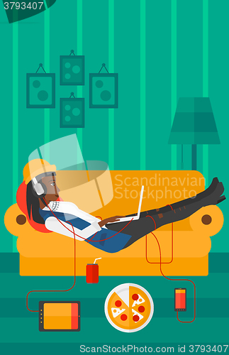Image of Woman lying on sofa with many gadgets.