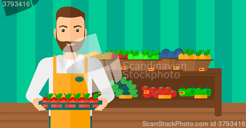 Image of Supermarket worker with box full of apples.