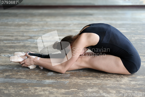 Image of Ballet dancer stretching out sitting on the floor