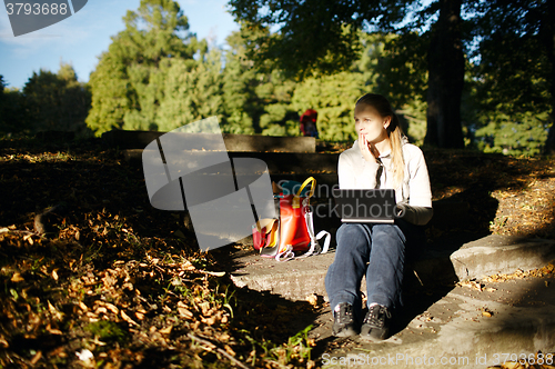 Image of Young woman working outdoors on a laptop