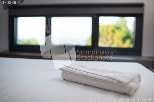 Image of Clean white towel on the bed in hotel room