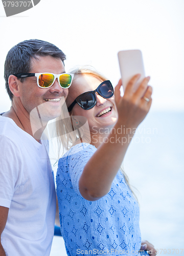 Image of Cheerful couple in sunglasses taking mobile selfie