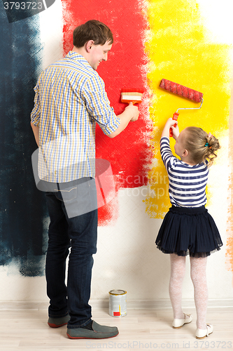 Image of Father and daughter painting wall