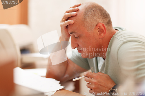 Image of Mature businessman smoking in the office