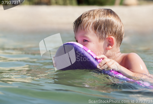 Image of Little boy swimming on board near the beach