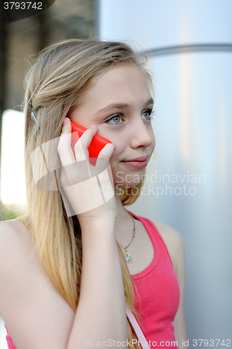Image of Young girl talking on the phone outdoor