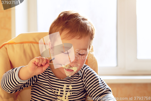 Image of Two year old boy eats porridge in the morning.