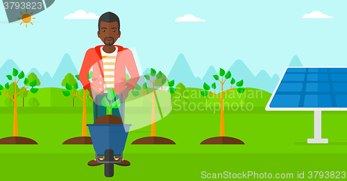 Image of Man with plant and wheelbarrow.