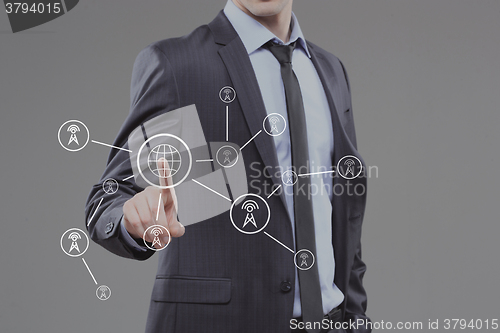 Image of business man pressing a touchscreen button. world map towers