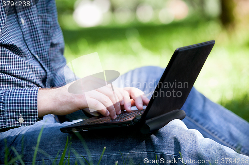 Image of Detail of hands and laptop keyboard.