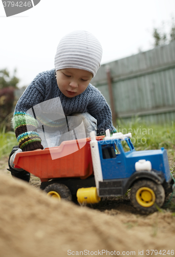 Image of Boy playing with toy truck outdoor