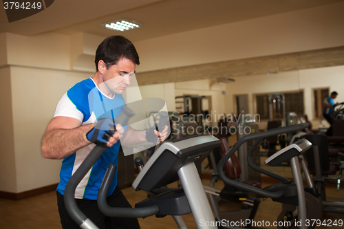 Image of Man exercising on elliptical machine in gym