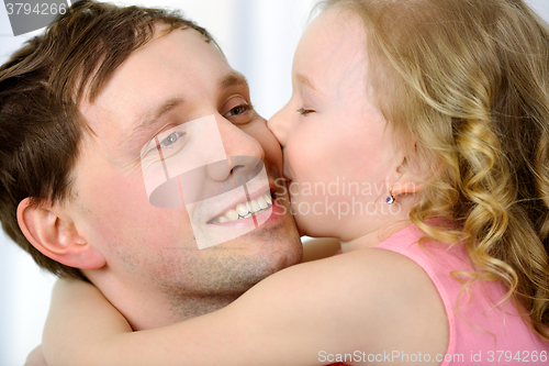 Image of Little girl kissing fathers cheek