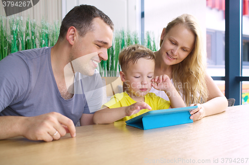 Image of Happy family of three with tablet computer in cafe