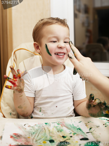 Image of Happy little boy doing finger painting