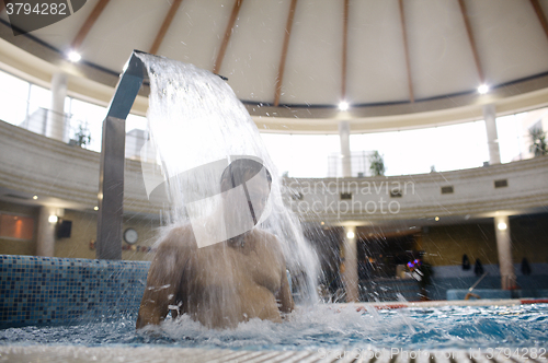 Image of Man under water stream in the swimming pool