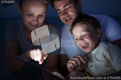 Image of Parents and son with tablet PC outdoor late in the evening