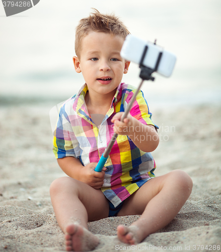 Image of Child with phone and selfie stick on the beach