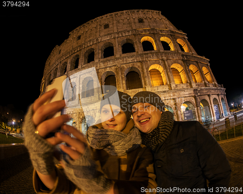 Image of Happy couple making selfie by Coliseum at night