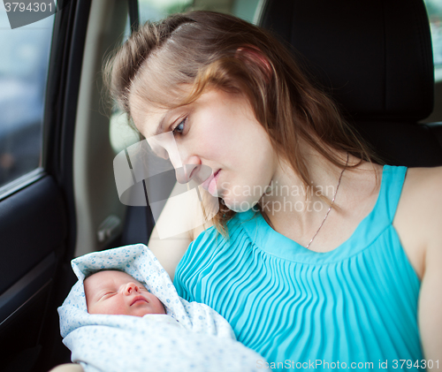 Image of Woman holding newborn baby sitting in the car