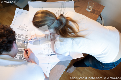 Image of Young architects working with map and blueprint