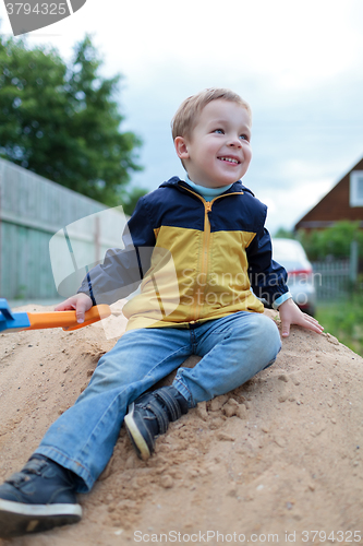 Image of Happy little boy sitting on sand hill